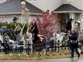 A visitor stops to take photos of the Halloween decorations at home, 9004 158 Ave., in Edmonton, Oct. 30, 2020.