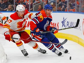Calgary Flames forward Connor Zary (47) and Edmonton Oilers defensemen Ryan Murray (28) battle for a loose puck during the second period at Rogers Place.