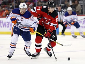 Connor McDavid #97 of the Edmonton Oilers battles Yegor Sharangovich #17 of the New Jersey Devils for the puck during the second period of the game at Prudential Center on Nov. 21, 2022 in Newark, New Jersey.