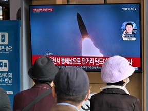 People watch a TV screen showing a news broadcast with file footage of a North Korean missile test, at a railway station in Seoul, Oct. 28, 2022.