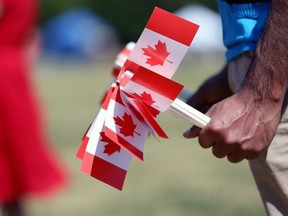 A volunteer holds souvenir Canadian flags to be distributed at Assiniboine Park in Winnipeg, July 1, 2019.
