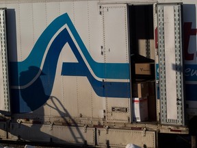 A worker's shadow is cast onto the side of a moving van as he walks down the ramp of the van.