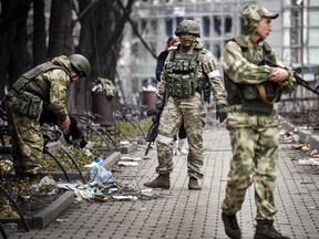 Russian soldiers walk along a street in Mariupol on April 12, 2022.