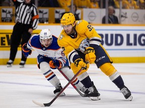NASHVILLE, TN - DECEMBER 13: Roland McKeown #55 of the Nashville Predators skates the puck against Kailer Yamamoto #56 of the Edmonton Oilers in a delayed penalty during the first period at Bridgestone Arena on December 13, 2022 in Nashville, Tennessee.