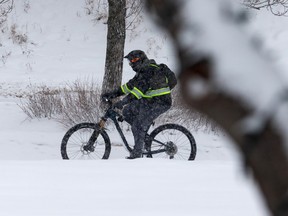 A cyclist rides on the bike lane next to Constable Ezio Faraone Park during a snowstorm in Edmonton, on Wednesday, Dec. 22, 2021. Photo by Ian Kucerak