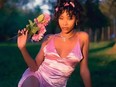 Beautiful young woman posing in pink dress and holding pink flowers.