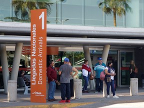 People stand outside the Culiacan International Airport which was reopened after being closed due to the violence caused by the detention of Mexican drug gang leader Ovidio Guzman, the 32-year-old son of jailed kingpin Joaquin "El Chapo" Guzman, in Culiacan, Mexico, Jan. 6, 2023.