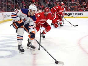 Dylan Holloway of the Edmonton Oilers tries to control the puck next to Joe Veleno of the Detroit Red Wings during the third period at Little Caesars Arena on Tuesday, Feb. 7, 2023, in Detroit, Michigan.