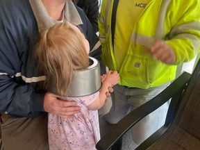 Girl with cake pan stuck on head and two firefighters.