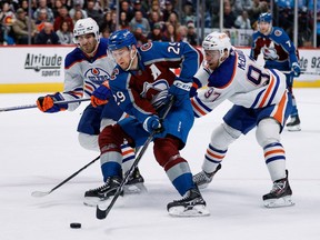 Feb 19, 2023; Denver, Colorado, USA; Colorado Avalanche center Nathan MacKinnon (29) controls the puck under pressure from Edmonton Oilers center Connor McDavid (97) and defenseman Evan Bouchard (2) in overtime at Ball Arena. Mandatory Credit: Isaiah J. Downing-USA TODAY Sports