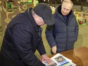 In this grab taken from video released by Russian broadcaster VGTRK as POOL on March 19, 2023, shows Russia's President Vladimir Putin (right) gesturing while speaking with Deputy Prime Minister Marat Khusnullin as they look at reconstruction illustrations while he visits the Ukranian city of Mariupol late March 18, 2023.