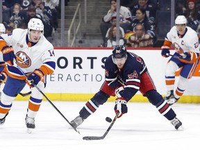 New York Islanders centre Bo Horvat (14) and Winnipeg Jets defenceman Dylan Samberg (54) chase for the puck in the first period at Canada Life Centre.