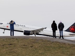 People look on as an Air Canada plane takes off from Trudeau Airport in Montreal, Sunday, Dec. 5, 2021.