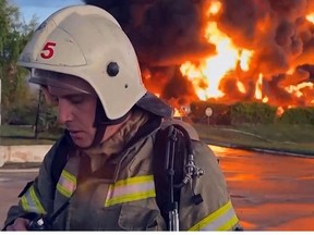 This video grab taken from a footage released on April 29, 2023, on the Telegram channel of Mikhail Razvozhayev, shows a firemen standing next to a huge fire at a fuel depot in Sevastopol.