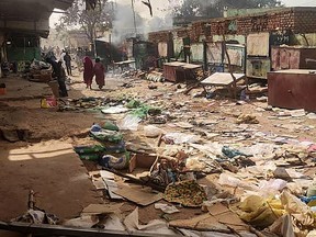 People walk among scattered objects in the market of El Geneina, the capital of West Darfur, as fighting continues in Sudan on April 29, 2023