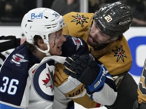 Vegas Golden Knights center Chandler Stephenson (20) helps Winnipeg Jets center Morgan Barron (36) after Barron cut his face on a skate during the first period of Game 1 of an NHL hockey Stanley Cup first-round playoff series Tuesday, April 18, 2023, in Las Vegas.