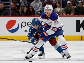 Edmonton Oilers center Connor McDavid (97) controls the puck under pressure from Colorado Avalanche centre Evan Rodrigues (9) in the first period at Ball Arena on Tuesday, April 11, 2023.