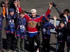 The Edmonton Oil Kings' Cole Miller poses for a photo with kids taking part in the street hockey tournament during the NHL Street Festival outside Rogers Place, in Edmonton Saturday April 15, 2023. Photo by David Bloom