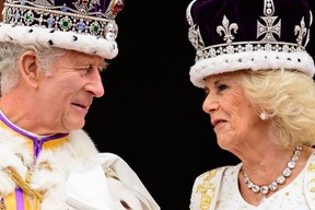 Britain's King Charles III (L) looks at Queen Camilla as they stand on the Buckingham Palace balcony, in London, following their coronations, on May 6, 2023.