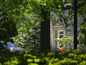 A construction worker walks past the front entrance to 24 Sussex Drive in Ottawa on Monday, May 29, 2023.