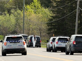 Ontario Provincial Police cars were parked outside a home on Laval Street in Bourget, Ont. Thursday morning. Police were on the scene of a shooting involving three OPP officers. One has died and another two were injured.