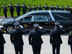Members of the Ontario Provincial Police salute as the vehicle carrying OPP Sgt. Eric Mueller leaves the grounds of the Canadian Tire Centre following a funeral in Ottawa, on Thursday, May 18, 2023. Sgt. Mueller was killed in the line of duty while responding to call on May 11 in the village of Bourget, Ont.