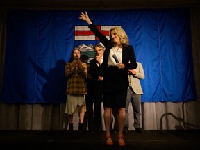 Rachel Notley stands on a stage, her family behind her, waving to supporters at the end of the night on election night.