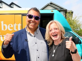 Naheed Nenshi stands smiling with his arm around Rachel Notley's shoulders, as she gives the thumb;s up to the camera