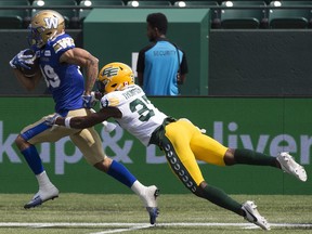 The Winnipeg Blue Bombers' Kenny Lawler (89) breaks a tackle from the Edmonton Elks' Dwayne Thompson II. (37) and scores a touchdown.