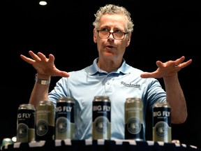 Edmonton Riverhawks' general manager Steve Hogle gestures at six cans of beer branded for the team through a partnershipd with Alley Kat Brewing.