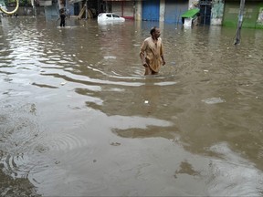 People wade through a flooded area caused by heavy monsoon rainfall in Lahore, Pakistan, on July 5, 2023. Eleven workers were killed early Wednesday July 19, 2023 after a portion of the outer wall of a sprawling compound collapsed after being weakened by rains near an under-construction bridge on the outskirts of Pakistan's capital, Islamabad, police and rescue officials said.