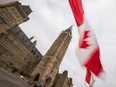 A Canadian flag flies in front of the Peace Tower on Parliament Hill in Ottawa. Government debt amassed during the pandemic will need to be serviced by taxes.