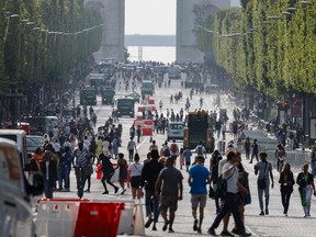 Pedestrians walk on Champs-Elysees avenue in Paris, on July 2, 2023, a day after protesters took to the street and clashed with police on an iconic street popular with tourists during a protest against the police killig of a 17-year-old teenage boy.