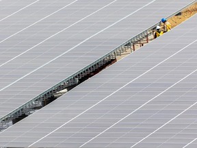 Construction workers near completion of the solar panels covering the parking lot at Telus Spark on March 14, 2022.