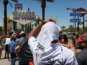 Satya Soviet Patnaik shields himself from the sun while waiting in line to take a photo at the historic Welcome to Las Vegas Sign during a heat wave in Las Vegas, Nevada, on July 14, 2023.