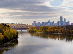 Edmonton's river valley is displaying fall colours as seen from the east, with the city skyline silhouetted in the background.