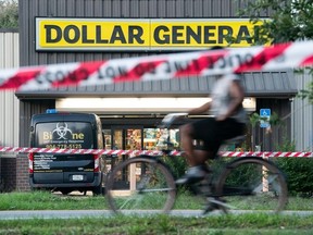 A bicyclist rides past the Dollar General store where three people were shot and killed the day before on August 27, 2023 in Jacksonville, Florida.