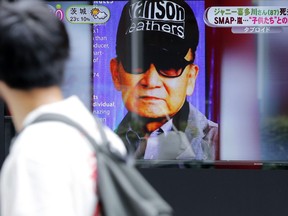 A passer-by watches a TV news reporting Johnny Kitagawa's passing away in Tokyo, on July 10, 2019. A growing number of people are alleging sexual abuse by Kitagawa, who ruled over Japanese entertainment for decades, founding and heading his talent agency, known as Johnny’s, reputed for being behind a string of boy-bands.