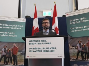 Federal Environment Minister Steven Guilbeault stands at a podium with a pair of Canadian flags in the background