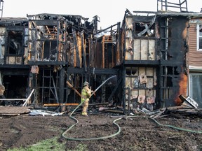 Two overnight fires displaced families in at least three townhouses on Hooke Road in northeast Edmonton. Fire crews remained on scene dowsing hot spots on August 29, 2023.