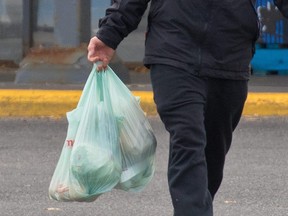 Shoppers leave the Real Canadian Superstore in Calgary with groceries in plastic bags on Wednesday, Oct. 7, 2020.