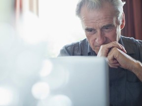 Senior man with hands clasped using laptop - stock photo. Getty Images