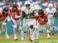 Essang Bassey of the Denver Broncos dives after De'Von Achane of the Miami Dolphins as Achane scores a touchdown.