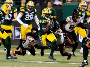 An Elks player runs with the football chased by a crowd of BC Lions players