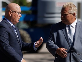 Ontario Premier Doug Ford, right, welcomes Minister of Housing Steve Clark to the podium during a press conference in Mississauga Friday, Aug. 11, 2023.