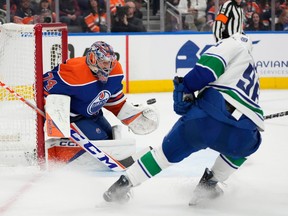 Oilers goaltender Stuart Skinner deflects a shot by a Vancouver player.