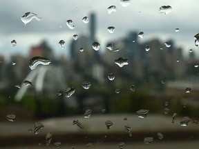 Rain drops on a window with downtown Edmonton city skyline in the background.