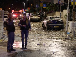 Israeli security forces stand along a debris-strewn street in Tel Aviv after it was hit by a rocket fired by Palestinian militants from the Gaza Strip on October 7, 2023. Palestinian militant group Hamas launched a surprise large-scale attack against Israel on Oct. 7, 2023.