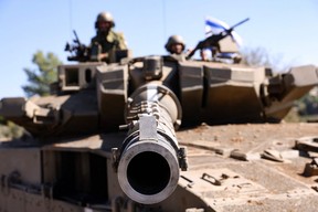 Israeli soldiers sit on a Merkava tank as they man a position at an undisclosed location on the border with Lebanon on Saturday, Oct. 21, 2023.