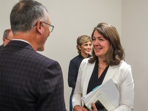 Premier Danielle Smith chats with Calgary Flames President and CEO John Bean, left, with Mayor Jyoti Gondek in the background following a new arena announcement on Thursday, October 5, 2023.